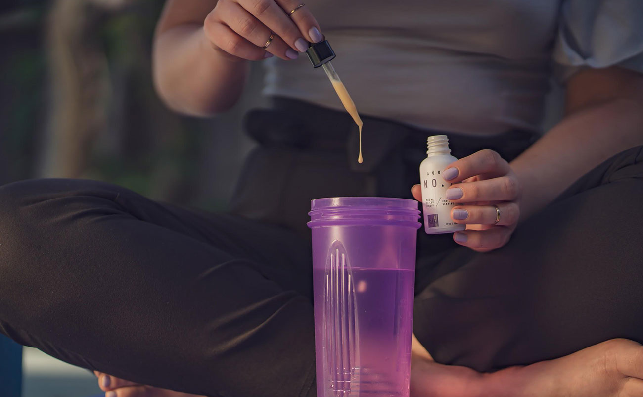 Woman adding her water-soluble CBD into a shaker cup